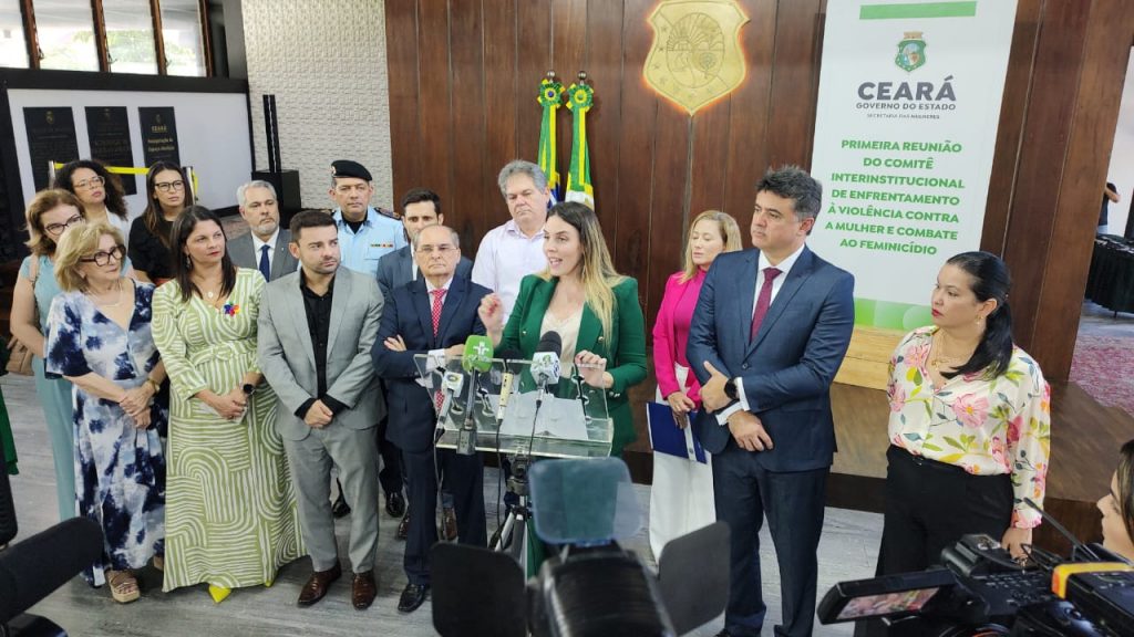 Imagem da vice-governadora do Ceará, Jade Romero, respondendo a perguntas de jornalistas em coletiva de imprensa. Enquanto discursa, Jade está rodeada por demais representantes da pasta da Segurança Pública, do Poder Judiciário, do Ministério Público e da Defensoria Pública